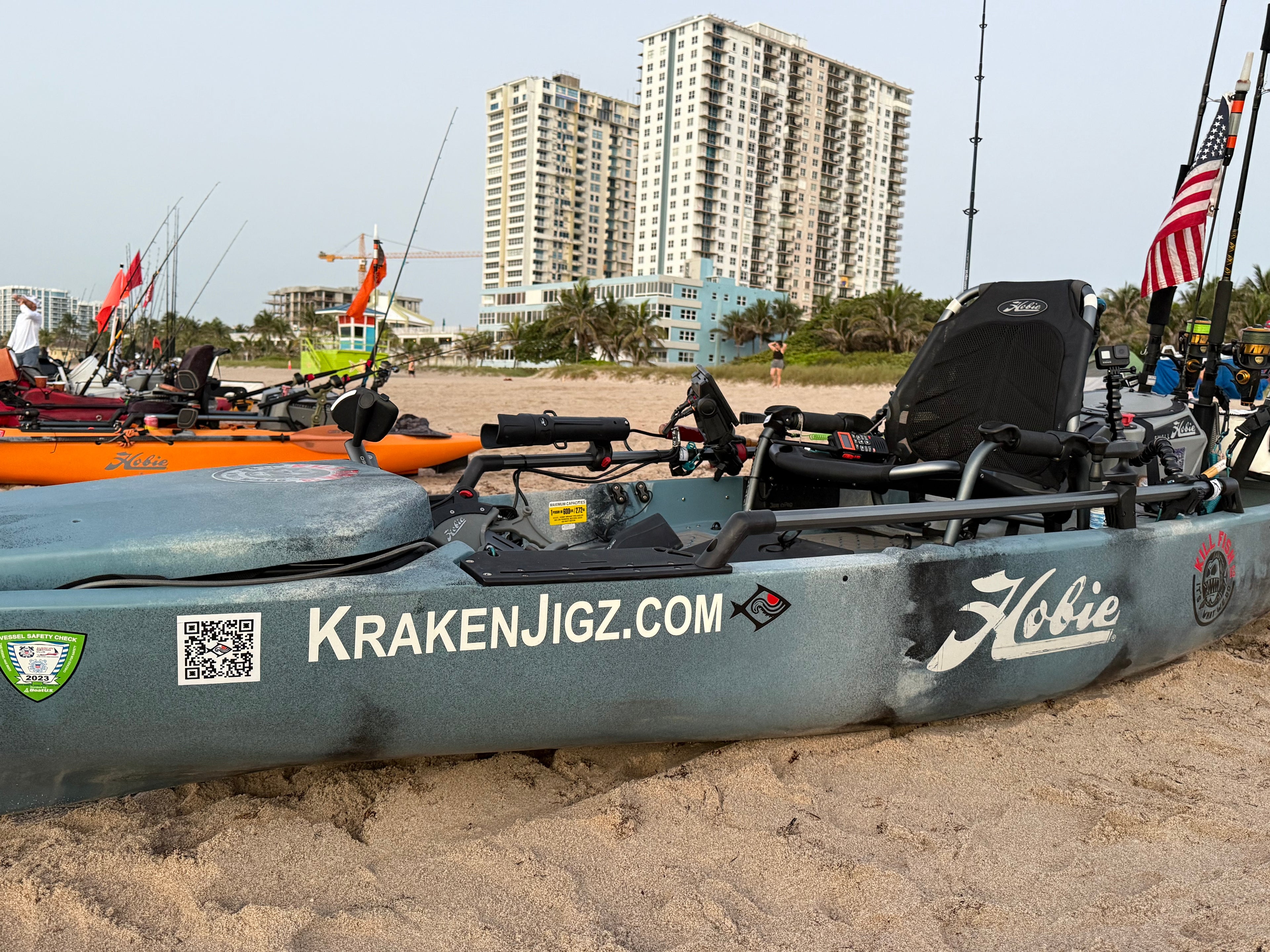 Kayaks on a sandy beach with kraken jigz logo